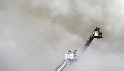 Una gran nube de humo cubre el cielo de la zona de Harlem en la que se han derrumbado dos edificios de viviendas. En la imagen, los bomberos trabajan en las labores de extinción del incendio provocado por la explosión.
