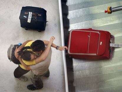 Una pareja de viajeros se abraza en el aeropuerto de Barajas.
