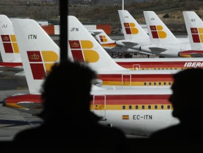 Unos pasajeros observan un aviones de Iberia en el aeropuerto de Barajas en Madrid. 