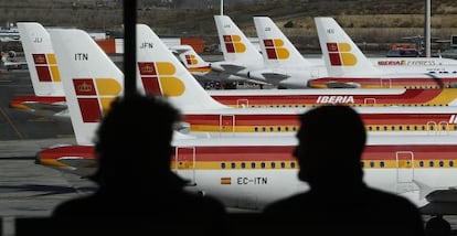 Unos pasajeros observan un aviones de Iberia en el aeropuerto de Barajas en Madrid. 