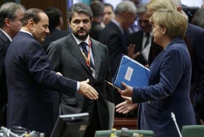 El primer ministro italiano, Silvio Berlusconi, saluda a la canciller alemana, Angela Merkel,  en la cumbre de ayer de Bruselas.