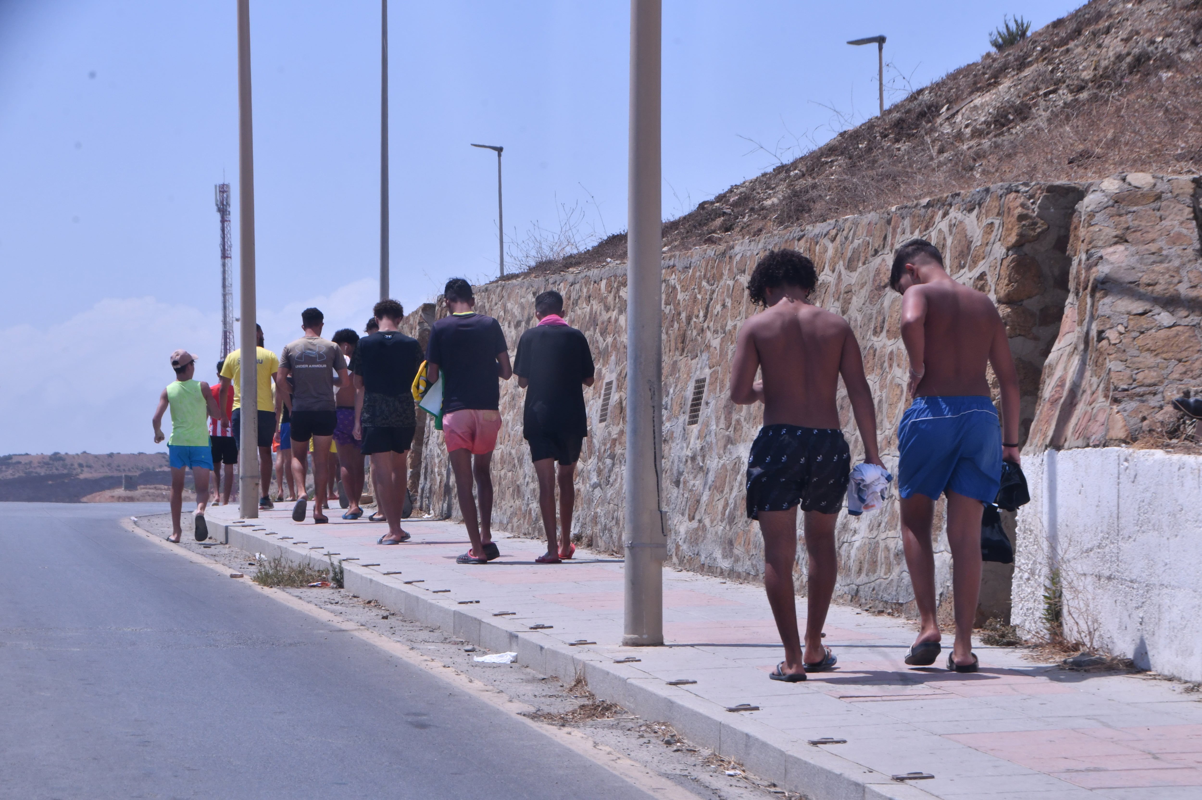 Un grupo de menores vuelven a  su centro de acogida, tras una mañana en la playa del Tarajal con un monitor.