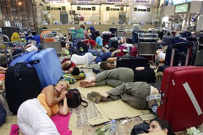 Decenas de personas duermen en el suelo junto a sus maletas en el aeropuerto de El Prat en la noche del viernes tras la cancelación de sus vuelos.