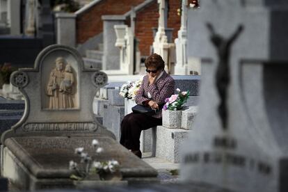 Una mujer reflexiona sentada sobre una tumba en el cementerio de La Almudena de Madrid.