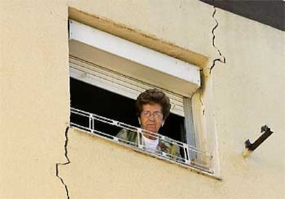 Una inquilina se asoma a la ventana de una de las viviendas afectadas por las grietas en San Cristóbal de los Ángeles.