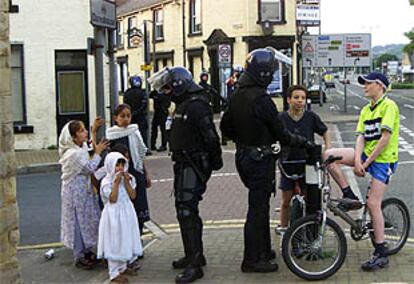 Niños de diferentes etnias charlan con policías antidisturbios en una calle de Londres.