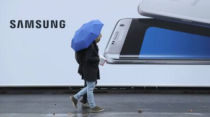 Unas personas pasean junto a un cartel publicitario de Samsung. 