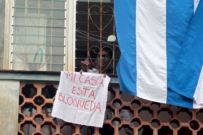 El disidente cubano Yunior García mira por la ventana de su vivienda con un cartel que indica "Mi casa está bloqueada'', el 14 de noviembre en La Habana.