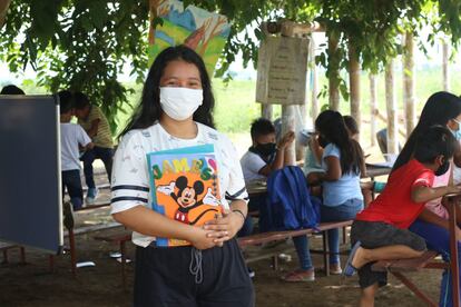 Dennisse posa para una foto mientras sus alumnos estudian. No hay ni un padre alrededor. No necesitan que les vigilen. “Empecé en mayo en el patio de mi casa con mis sobrinos y luego nos vinimos bajo el árbol. Los otros niños se acercaban y decían que querían pertenecer, pero yo les decía que no era una escuela”. En noviembre, cuenta, apareció personal del Municipio de Guayaquil. ¿Tuviste algún problema por dar clases presenciales a todos juntos estando en pandemia? “No, todos usan mascarilla y nos ponemos alcohol en las manos. Vinieron a ayudarnos. Enviaron a dos docentes que dedicaban media hora al día a cada niño por separado”.