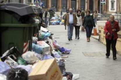 Varias personas caminan por las calles de la localidad gaditana de Jerez de la Frontera, donde se acumulan ya más de tres mil toneladas de basuras debido a la huelga de los trabajadores del servicio de limpieza.