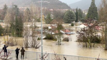Varias personas miran las inundaciones causadas en la localidad de Villava (Navarra). El jueves al mediodía se activó la fase 2 de emergencia del Plan Especial ante el Riesgo de Inundaciones.