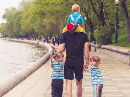 Un padre pasea con sus tres hijos.