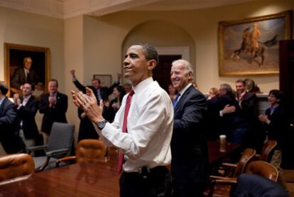 Barack Obama y su vicepresidente, Joe Biden (a su derecha), aplauden en la sede presidencial la aprobación de la reforma sanitaria.