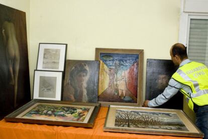 An agent arranges the stolen paintings, which were found in a house in Valdemoro.