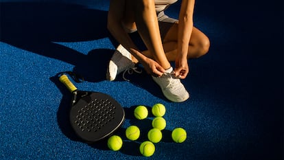Una chica preparandose para jugar al pádel con pala y pelotas.