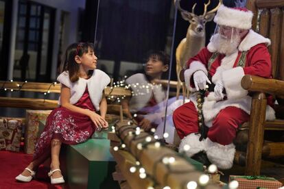 Gracelynn Blumenfeld, de 8 años, visita a Papá Noel a través de un cristal en un Bass Pro Shop en Bridgeport, Connecticut (Estados Unidos). Los centros comerciales están haciendo todo lo posible para mantener al alegre anciano a salvo del coronavirus.