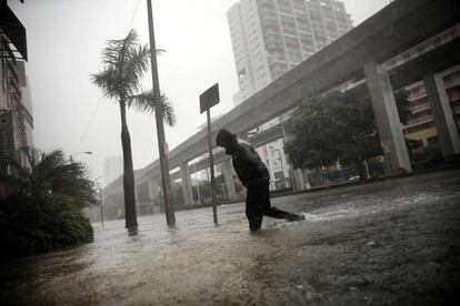 Un hombre caina bajo la lluvia en una calle inundada por el huracán, en Miami (Florida).
