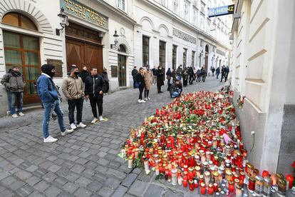 Varios transeúntes ante flores y velas dejadas en homenaje a las víctimas en uno de los puntos del atentado del lunes en Viena.