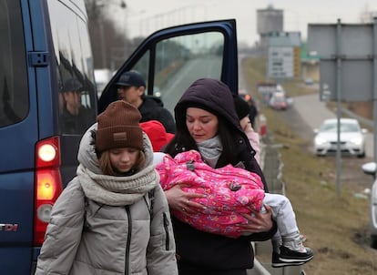 Una mujer sostiene un niño antes de cruzar la frontera de Ucrania con Polonia por el paso de Dorohusk.