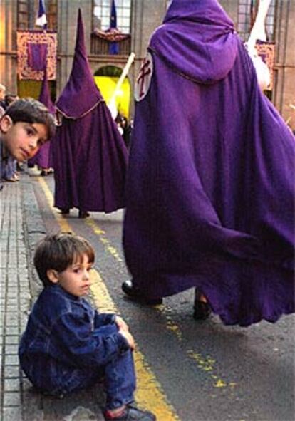 En una calle de La Laguna, (Tenerife) dos niños contemplan el paso de la procesión del Lignum Crucis y la Piedad.