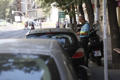 Un agente de movilidad revisando en la Calle San Bernardo que los coches aparcados cumplan con los requisitos previstos en el protocolo anticontaminación, que prohíbe el estacionamiento a los no residentes en la almendra central al aplicarse el nivel 2 por alta contaminación.