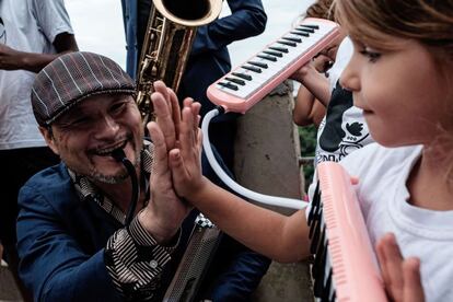 Membro da Tokyo Ska Paradise Orchestra, do Japão, compara sua mão com a de uma menina durante um workshop de música na favela do Pereirão, no Rio de Janeiro, em 20 de novembro.