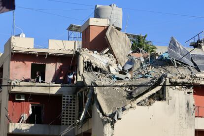 Varias personas inspeccionan un edificio afectado por un ataque israelí en Sidón (Líbano), este domingo.  