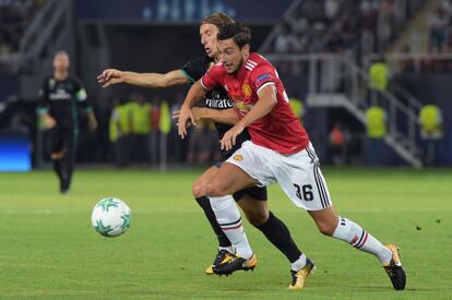 El defensa del Manchester United Matteo Darmian lucha junto al jugador del Real Madrid Luka Modric por hacerse con la posesión del balón.