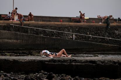 Una mujer toma el sol en una rampa para pequeñas embarcaciones en la playa de Arinaga, en el municipio grancanario de Agüimes.