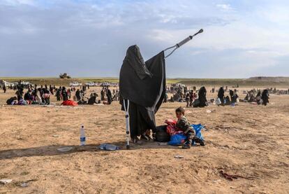 Uma mulher com muletas espera com o filho na área de registro de evacuados de Baghuz, no dia 5 de março.