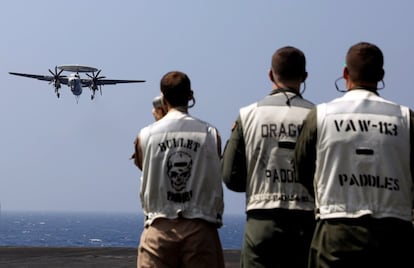 Algunos miembros de la tripulación de vuelo observan el avión de vigilancia de la Armada estadounidense E2C Hawkeye mientras aterriza en la cubierta del portaviones USS Carl Vinson.