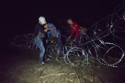 Varios inmigrantes cruzan la alambrada que delimita los países de Hungría y Serbia. Las autoridades húngaras estudian desplegar al Ejército en la frontera.