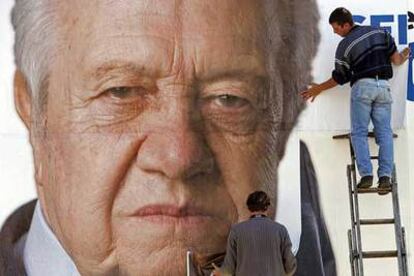Dos trabajadores colocan un cartel electoral del socialista Mário Soares, el pasado martes en Lisboa.