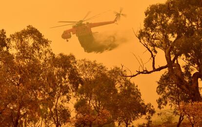 Un helicóptero arroja agua sobre un incendio forestal cerca de la ciudad de Bumbalong, al sur de Canberra (Australia), este domingo.