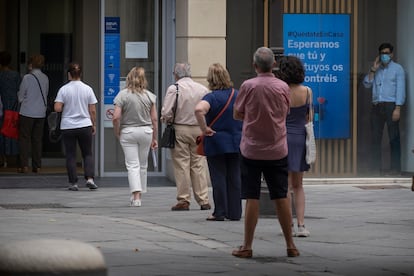 Varias personas esperan su turno en la calle para entrar en un banco en Sevilla, este lunes.