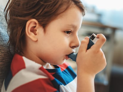 Un niño con asma usa su inhalador.