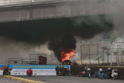 Los manifestantes se esconden detrás de una barricada de neumáticos en llamas en la calle principal que conduce a la Asamblea Nacional en Quito durante las protestas de transportistas. El sector del transporte fue el que primero se movilizó ante el paquete de ajustes anunciado por Moreno.
