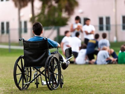 Un adolescente en silla de ruedas observa a sus compañeros jugando en el parque mientras le excluyen.