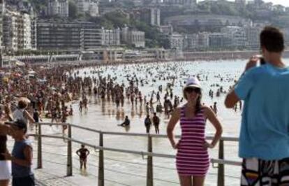 Dos turistas se fotografían junto a la playa de La Concha de San Sebastián. EFE/Archivo