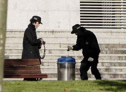 Agentes de la Ertzaintza intentan extraer pruebas de la papelera donde ETA colocó la bomba trampa.