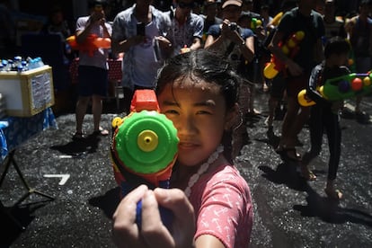 Una niña apunta con una pistola de agua al fotógrafo durante el Festival del Agua o Songkran en Bangkok (Tailandia).