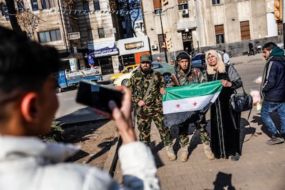 A woman poses with insurgents holding the flag of the new Syria, Tuesday in Homs.