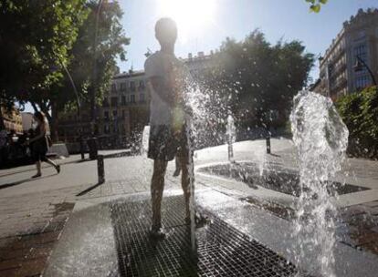 Un niño se refresca en las fuentes de la plaza de Tirso de Molina, en Centro.