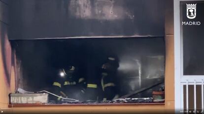 Dos bomberos, durante la extinción del fuego que ha afectado a una vivienda de la calle de Telémaco en Madrid.
