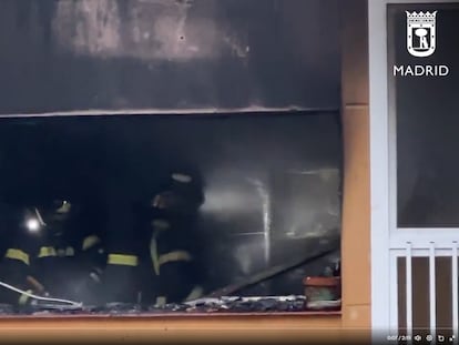 Dos bomberos, durante la extinción del fuego que ha afectado a una vivienda de la calle de Telémaco en Madrid.