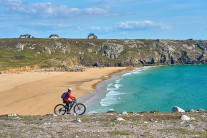 Una mujer pasea en bicicleta eléctrica por Finisterre, Francia.