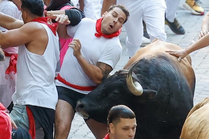 Un mozo es golpeado por uno de los toros de la ganadería Álvaro Núñez a su paso por la calle Estafeta.