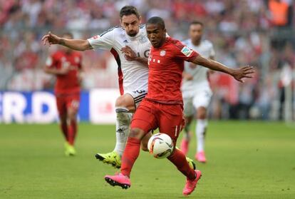 Douglas Costa se lleva un balón ante el acoso de Hilbert del Bayer Leverkusen