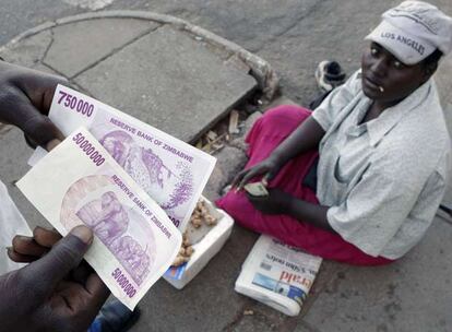 Un cambista muestra un billete de 50 millones de dólares zimbabuenses en un mercado informal de cambio de Harare.