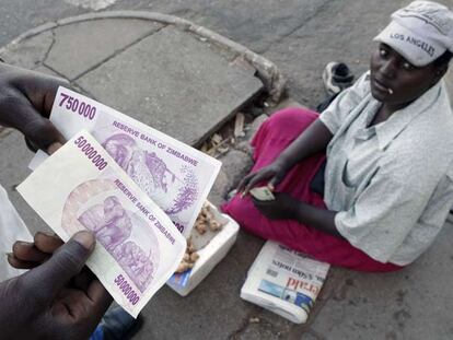 Un cambista muestra un billete de 50 millones de dólares zimbabuenses en un mercado informal de cambio de Harare.